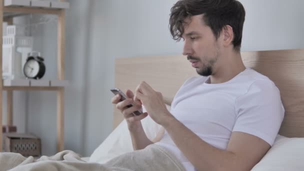 Casual Giovane Uomo Che Reagisce Alla Perdita Tramite Telefono Letto — Video Stock