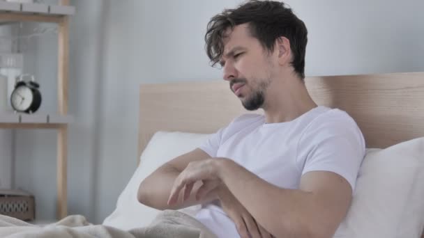 ベッドに座って首の痛みと疲れの若い男 — ストック動画