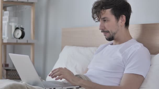 悲伤的年轻人在床上使用笔记本电脑时面临损失 — 图库视频影像