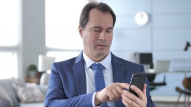 Orta yaşlı işadamı tepki Smartphone kullanarak süre kaybı