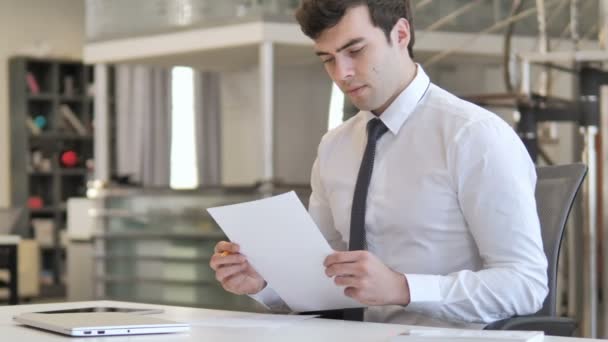 Joven empresario pensativo leyendo contrato en la oficina — Vídeos de Stock