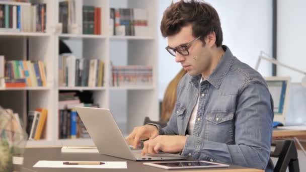 Уставший креативный человек с болью в шее работает над ноутбуком — стоковое видео