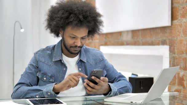 Afrikanske mand reagerer på tab på smartphone i Loft Office – Stock-video