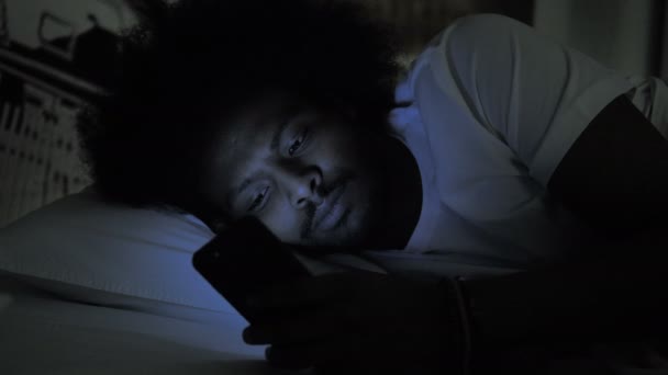 Africain utilisant le téléphone dans le lit la nuit — Video