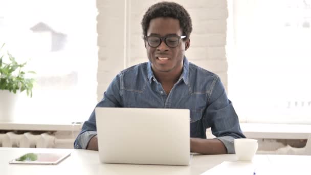 Уставший африканский человек с болью в шее во время работы над ноутбуком — стоковое видео