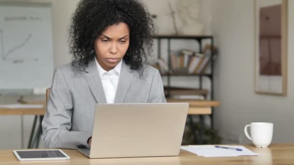 Schockierte afrikanische Geschäftsfrau fragt sich und arbeitet am Laptop — Stockvideo