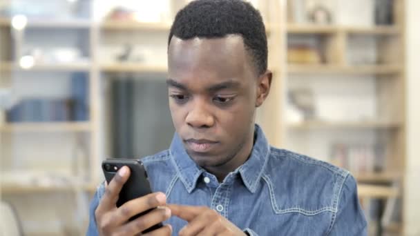 Hombre africano reaccionando a la pérdida en el teléfono inteligente — Vídeos de Stock