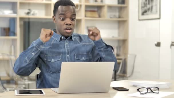 Hombre africano celebrando el éxito mientras trabaja en el ordenador portátil — Vídeo de stock