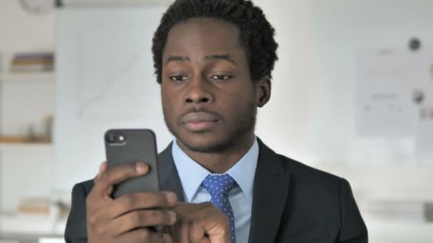นักธุรกิจแอฟริกันอารมณ์เสียโดยการสูญเสียบนสมาร์ทโฟน — วีดีโอสต็อก