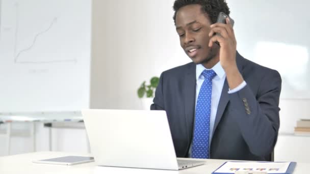 Afrikaans zakenman in gesprek over de telefoon op het werk — Stockvideo