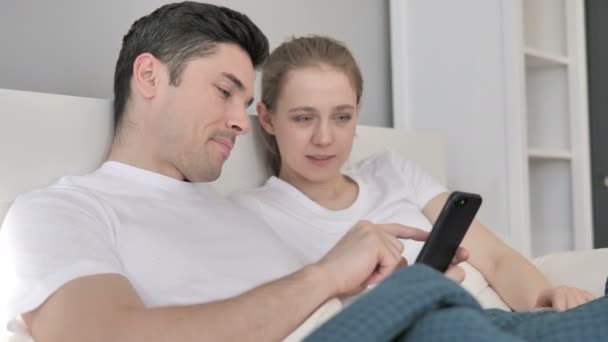 Young Couple Using One Smartphone in Bed — Stock Video