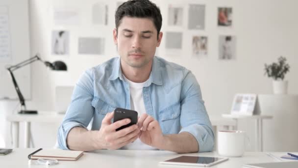 Lässiger junger Mann feiert Erfolg auf dem Smartphone — Stockvideo