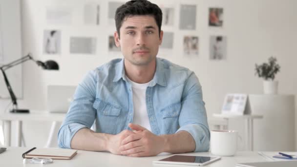 Casual ung man i chock sitter på arbetsplatsen — Stockvideo