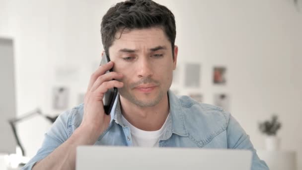 Случайный молодой человек разговаривает по телефону с клиентом — стоковое видео