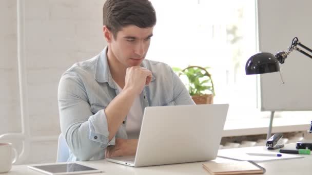Tänkande ung man som arbetar på laptop — Stockvideo
