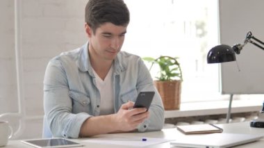 Genç adam akıllı telefon kullanıyor.