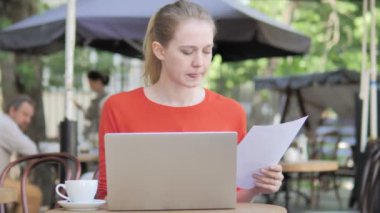 Genç Kadın Okuma Sözleşme ve Cafe Terrace Oturan Laptop Kullanma