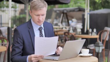 İşadamı Açık Kafede Otururken Belgeleri Okuyor