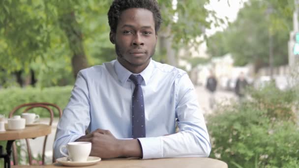 Sonriente empresario africano sentado en un café al aire libre — Vídeos de Stock