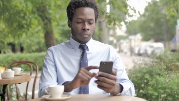 Afrikalı İşadamı Smartphone Kaybı üzgün, Açık Cafe oturan — Stok video