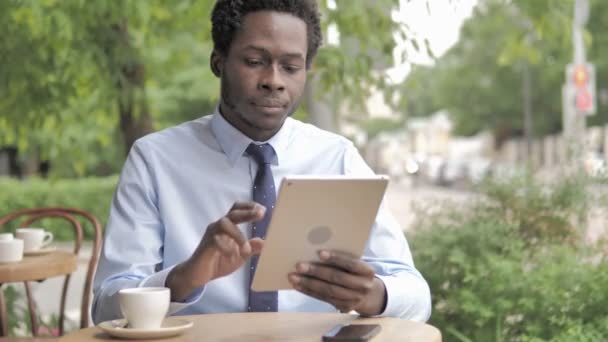 Африканський бізнесмен за допомогою планшета, сидячи у відкритому кафе — стокове відео