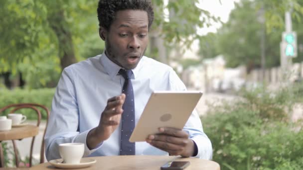 Wow, schockierter afrikanischer Geschäftsmann benutzt Tablet während er im Café sitzt — Stockvideo