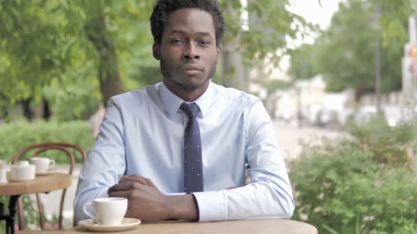 Retrato del hombre de negocios africano sonriente sentado en el café al aire libre — Vídeos de Stock