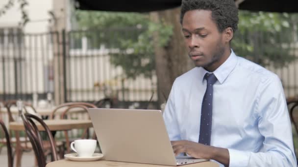 屋外カフェでラップトップを使用して頭痛を持つアフリカのビジネスマン — ストック動画