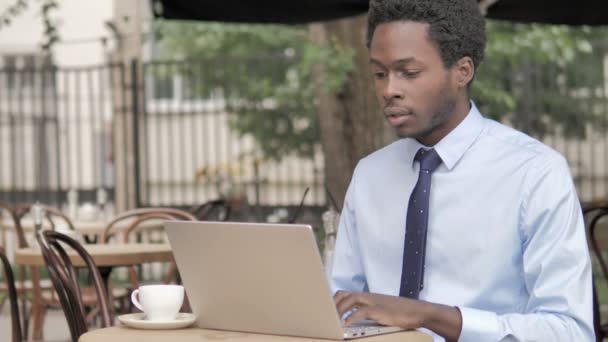 Homme d'affaires africain à choc par les résultats sur ordinateur portable dans un café en plein air — Video