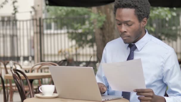アフリカのビジネスマンは契約を読み、屋外カフェでラップトップを使用 — ストック動画