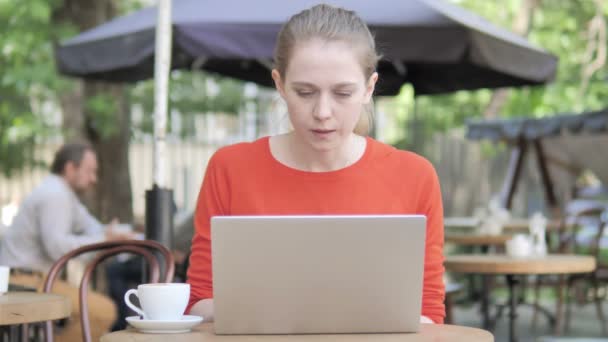 Junge Frau steht unter Schock, als sie auf der Caféterrasse am Laptop sitzt — Stockvideo