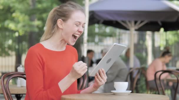 タブレットで勝利を祝う若い女性、カフェテラスに座って — ストック動画