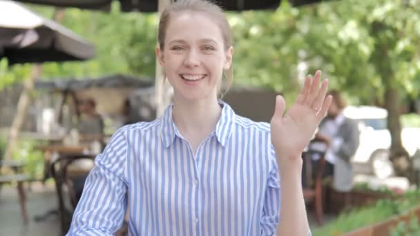 Hallo von einer jungen Frau, die auf der Caféterrasse sitzt — Stockvideo