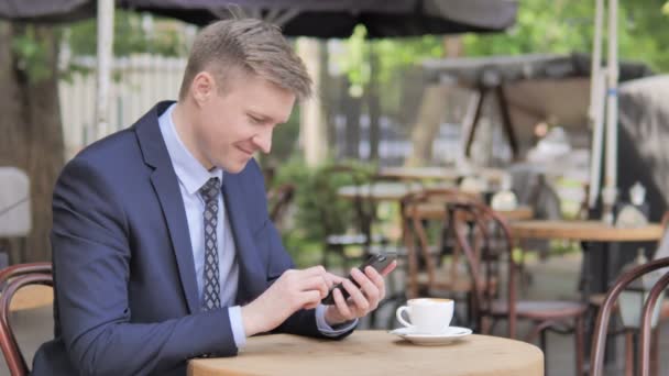 Affärsman använder smartphone sitter i utomhus Café — Stockvideo