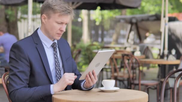 Empresario celebrando victoria en la tableta, sentado en el café al aire libre — Vídeo de stock