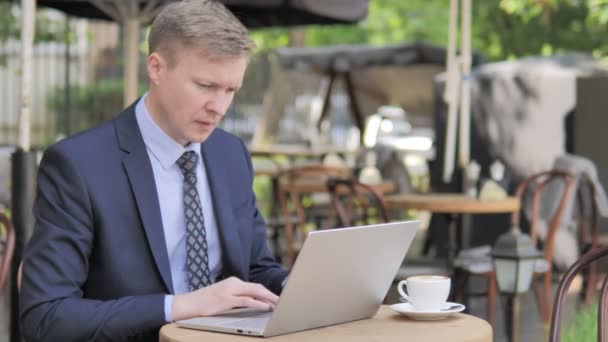 Кашель Бизнесмен работает на ноутбуке в открытом кафе — стоковое видео
