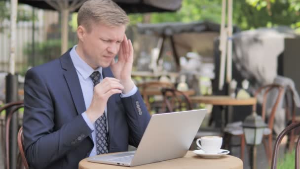 Zakenman met hoofdpijn met behulp van laptop in outdoor cafe — Stockvideo