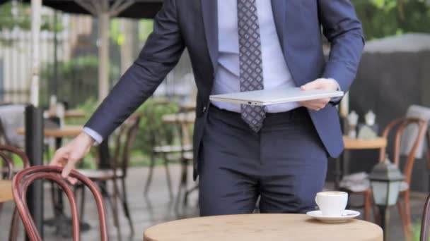 Geschäftsmann kommt und sitzt in Café-Terrasse, um Laptop zu benutzen — Stockvideo