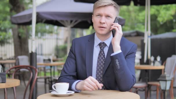 Empresário falando ao telefone enquanto relaxa ao ar livre — Vídeo de Stock