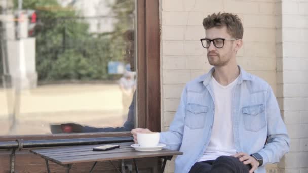 Draußen sitzender junger Mann trinkt Kaffee — Stockvideo