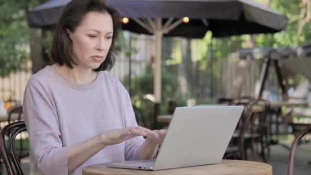 Mujer vieja con dolor de cabeza usando el ordenador portátil, sentado al aire libre — Vídeos de Stock