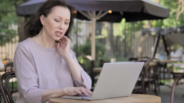 Gammal kvinna med nacksmärta använda laptop utomhus — Stockvideo