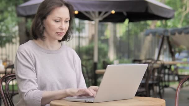 Stara kobieta obchodzi sukces na laptopie, siedząc na zewnątrz — Wideo stockowe