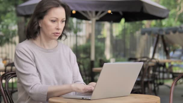 Stary kobieta wstrząśnięty przez wyniki na laptop, siedzący na wolnym powietrzu — Wideo stockowe