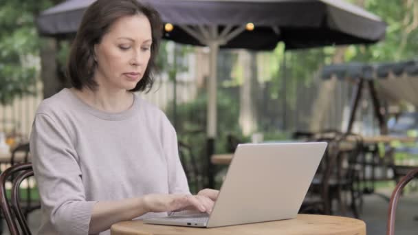 Zdenerwowany stara kobieta reaguje na utratę na laptopie, siedząc na zewnątrz — Wideo stockowe