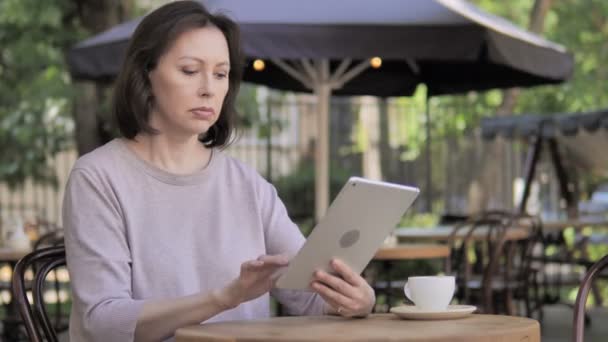 Molesto anciana reaccionando a la pérdida en la tableta en el café al aire libre — Vídeos de Stock