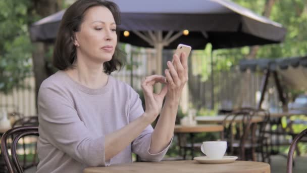 Öregasszony beszélő-ra telefon, ülő-ban szabadban történő kávézó — Stock videók