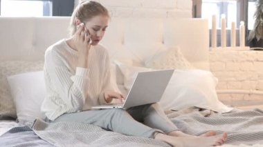 Yatakta Otururken Ve Dizüstü Bilgisayar Kullanırken Telefonda Konuşan Kadın