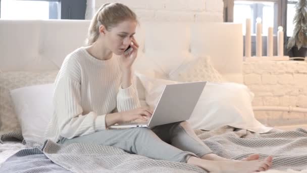 Mujer enojada hablando por teléfono mientras está sentada en la cama, luchando — Vídeo de stock