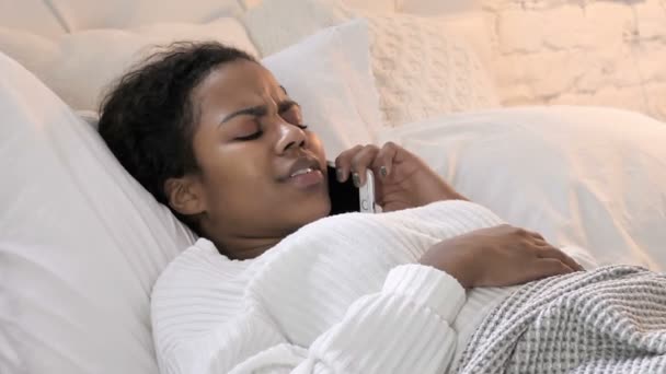Joven mujer africana hablando por teléfono mientras está acostada en la cama — Vídeo de stock